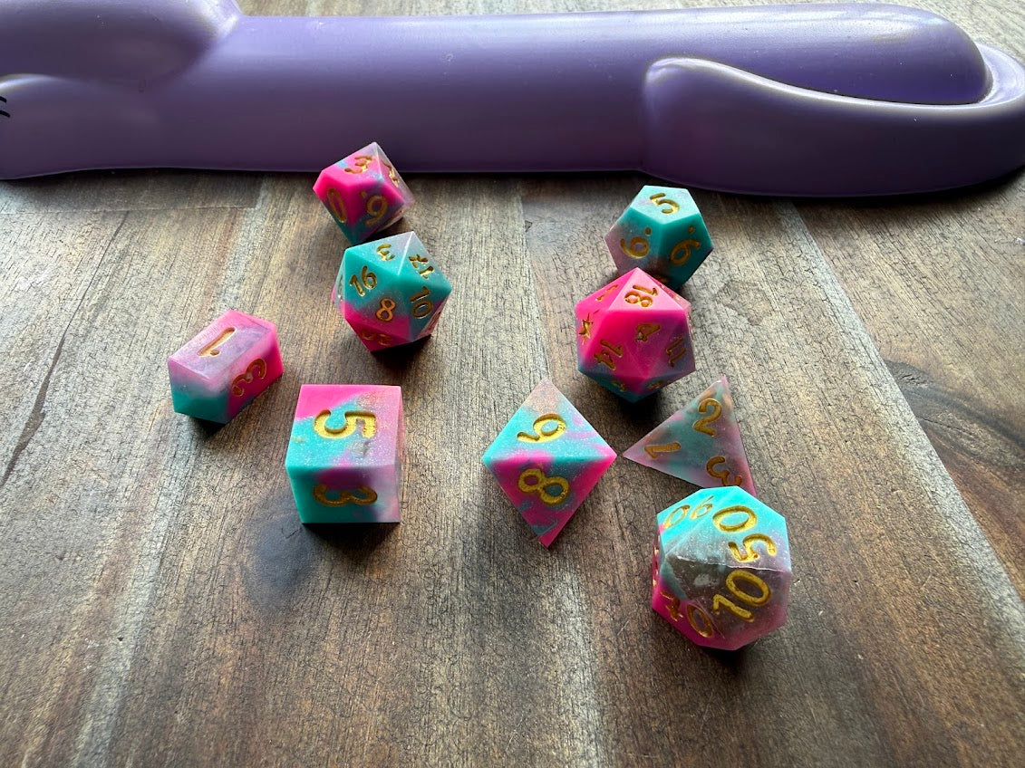 Set of copper-colored polyhedral dice on a wooden surface with a purple object in the background.
