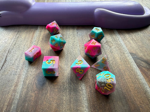 Set of copper-colored polyhedral dice on a wooden surface with a purple object in the background.