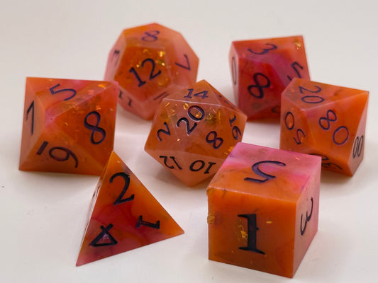 A set of 7 orange and red, swirled polyhedral dice on a table. 