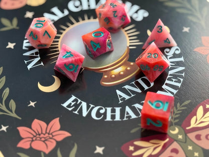 Pink polyhedral dice with green numbers on a decorative background