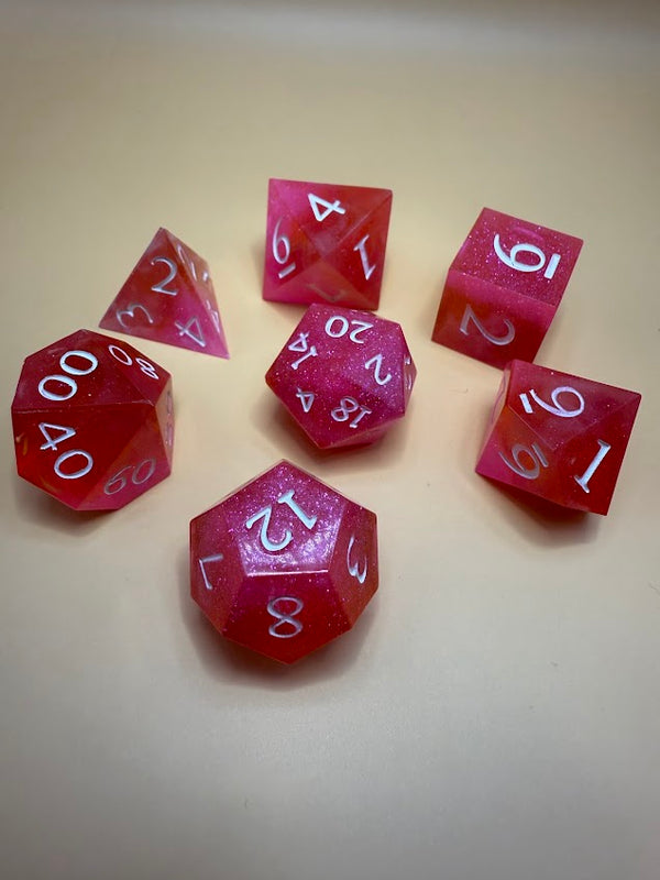 Set of red glittery polyhedral dice with white numbers on a beige background, tabletop gaming