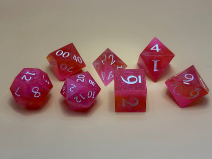 Set of pink polyhedral dice with white numbers on a beige background