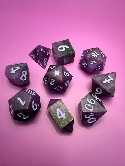 Purple polyhedral dice set on a pink background