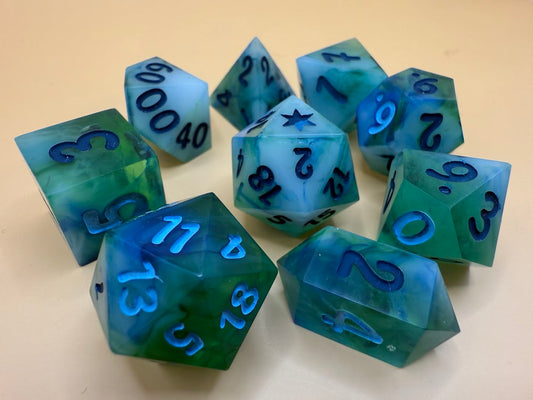 Set of blue and green polyhedral dice with black numbers on a beige background
