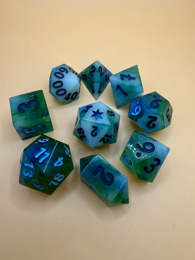 Set of green and blue polyhedral dice on a beige background
