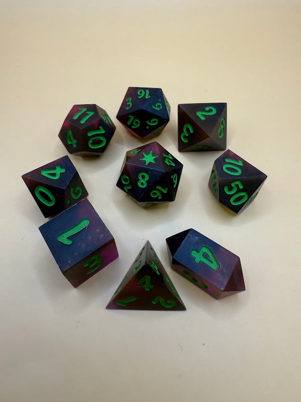 Handmade polyhedral dice set in dark red and purple with green numbers on beige background