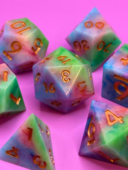 Colorful polyhedral dice with gold numbers on a pink background