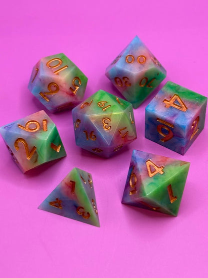 Set of colorful polyhedral dice with gold numbers on a pink background