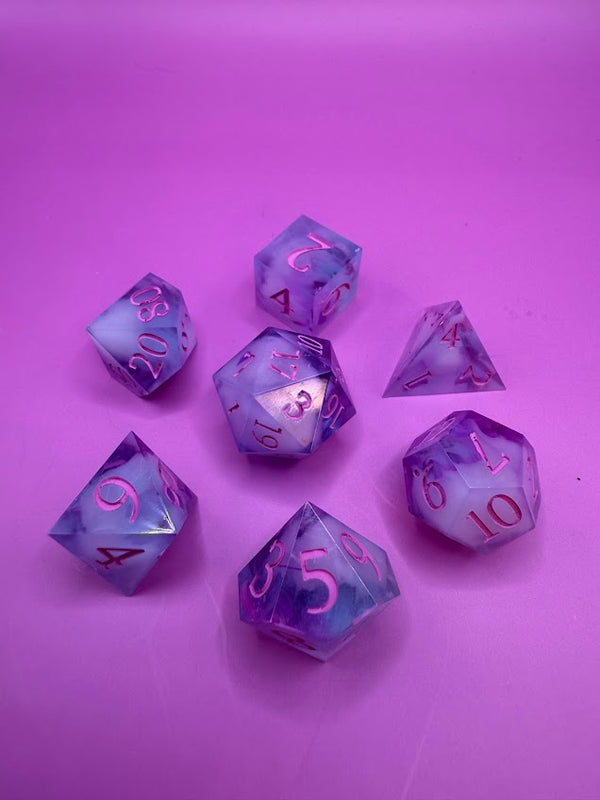 Hand-poured purple and white polyhedral dice set with pink numbers on a violet background