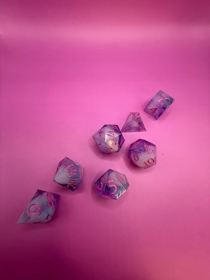 Purple and pink polyhedral dice set on a pink background