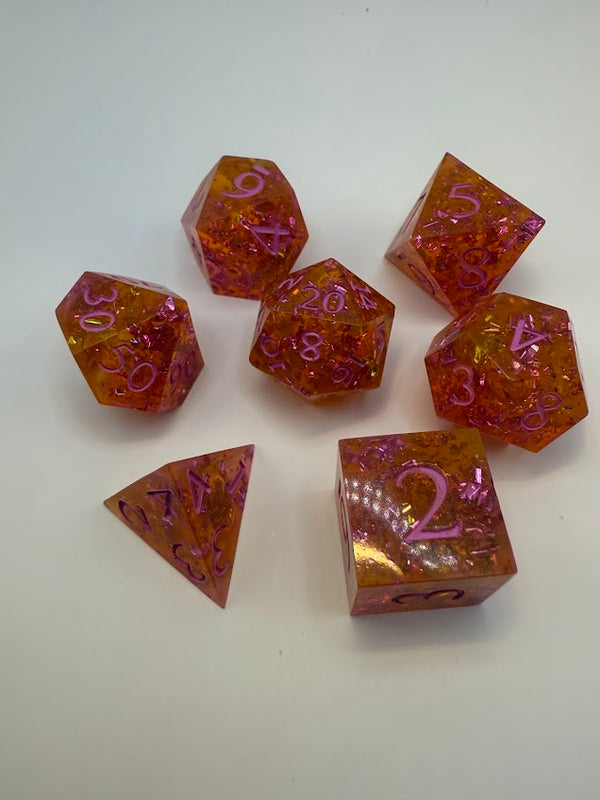 Handmade red and gold polyhedral dice set with pink numbers on white background
