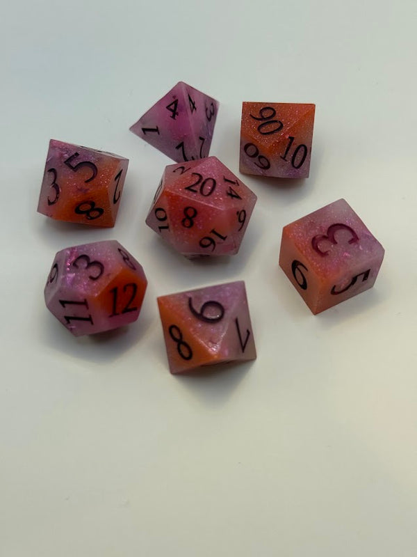 Set of seven shimmering pink and orange polyhedral RPG dice on white background