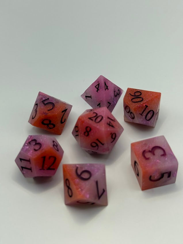 Set of pink polyhedral dice with black numbers on a white background
