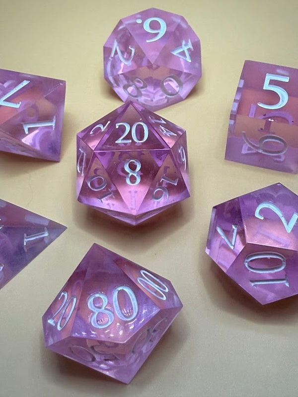 Set of translucent purple polyhedral RPG dice with white numbers on a tan background