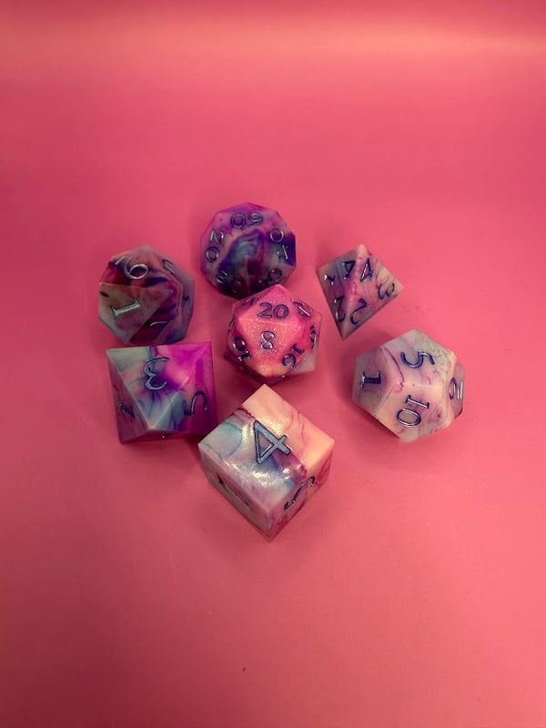 Handmade pink and purple resin polyhedral dice set on a pink background for tabletop RPGs