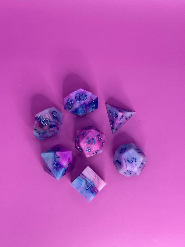 Colorful polyhedral dice on a pink background