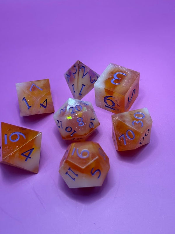 Handmade orange and white resin polyhedral dice set on a pink background