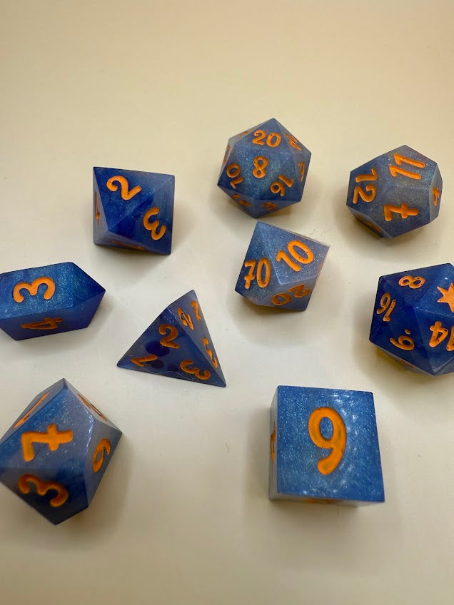 Blue polyhedral dice with orange numbers on a beige surface