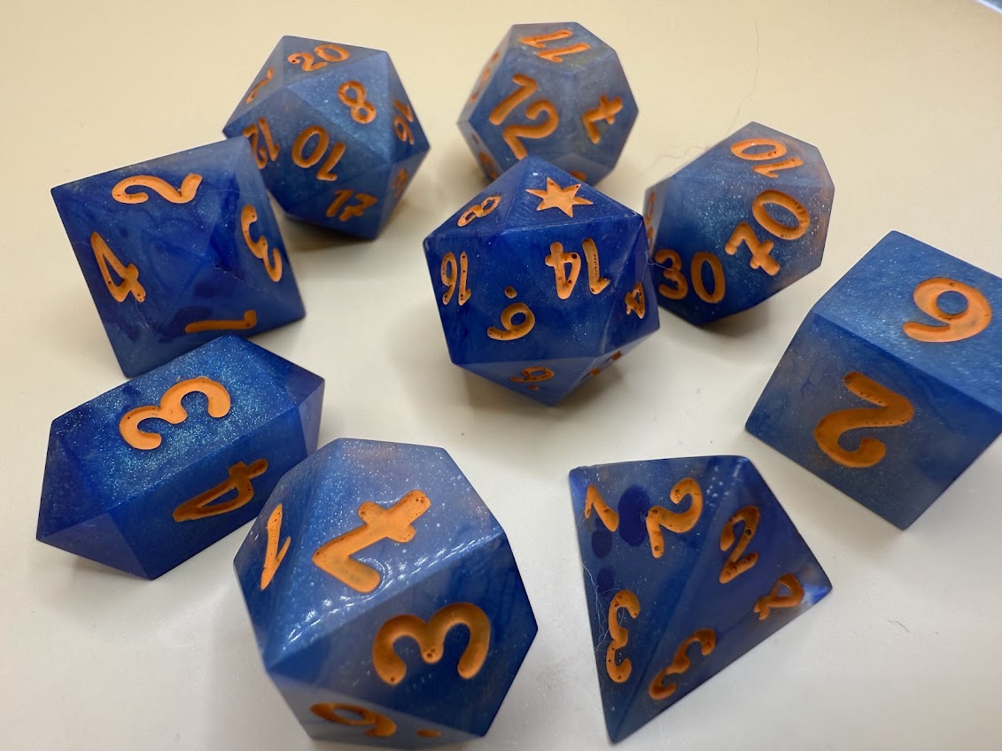 Blue polyhedral dice with orange numbers on a white background
