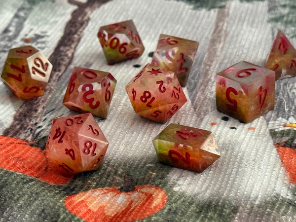 Handcrafted polyhedral dice set with red numbers and earthy tones on a patterned fabric