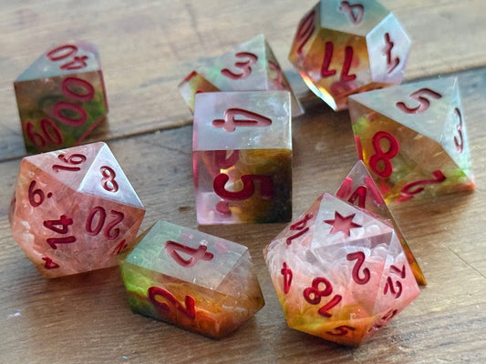 Set of colorful polyhedral dice with red numbers on a wooden surface