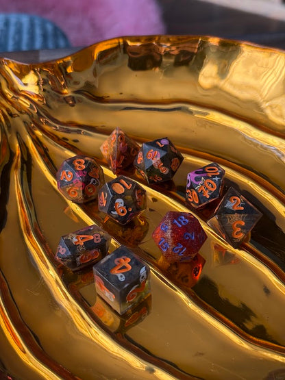 Set of polyhedral dice with metallic blue and red colors on a reflective gold surface.