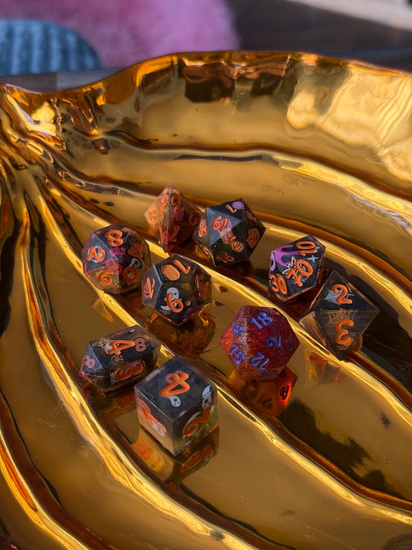 Colorful polyhedral dice set with red and orange numbers on a gold tray, tabletop gaming dice