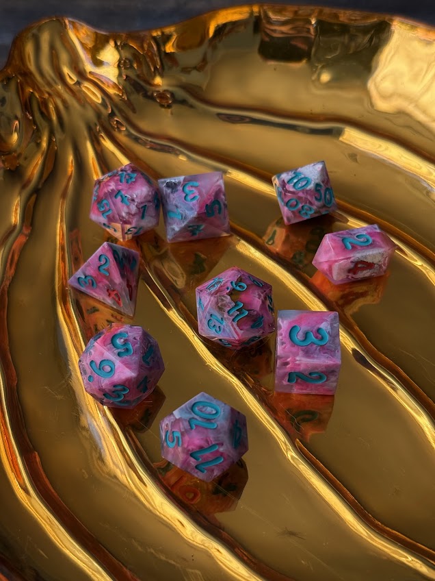 Pink and blue dice with numbers on a gold surface