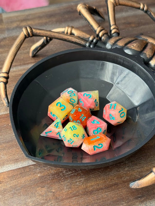 Colorful dice with numbers in a spider-shaped bowl on a wooden surface
