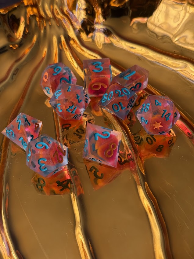 Hand-poured red dice set with blue numbers and star details on a gold background.