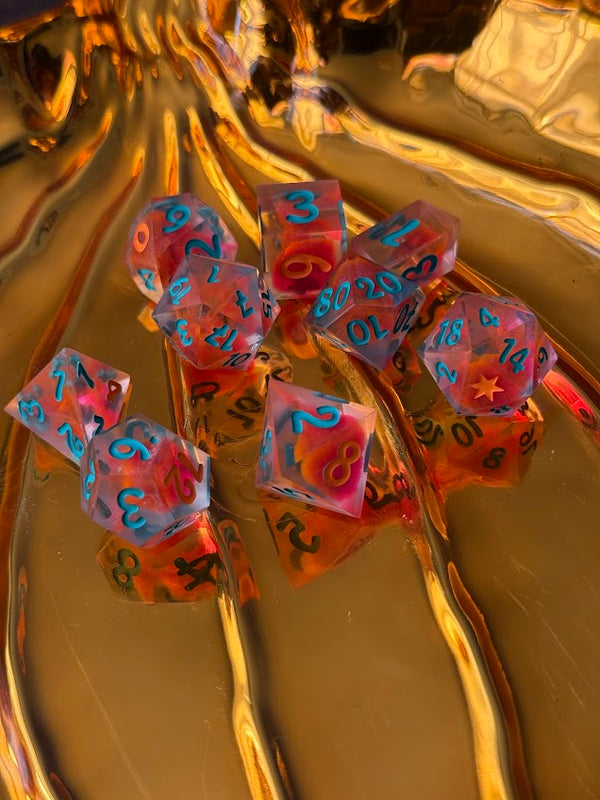 Hand-poured red dice set with blue numbers and star details on a gold background.