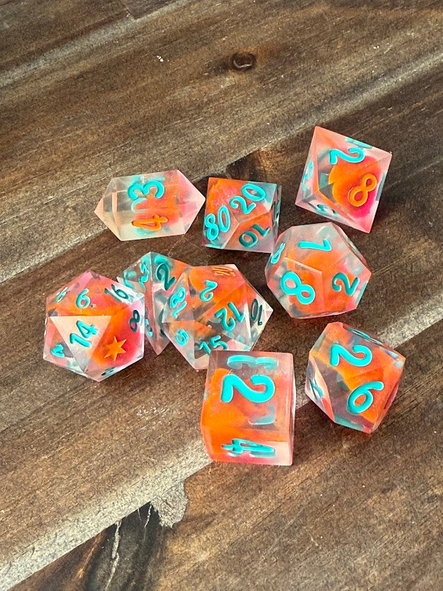 Handmade red and orange polyhedral dice set with blue numbers on wood table