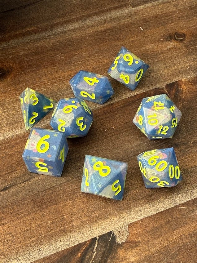 Handmade blue polyhedral dice set with yellow numbers on wooden table