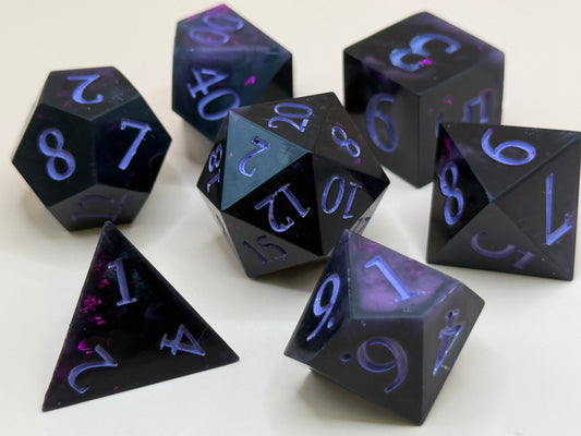 Set of black polyhedral dice with purple numbering on a white background