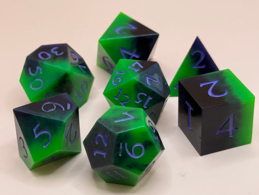 Set of green and black polyhedral dice with purple numbers on a white background
