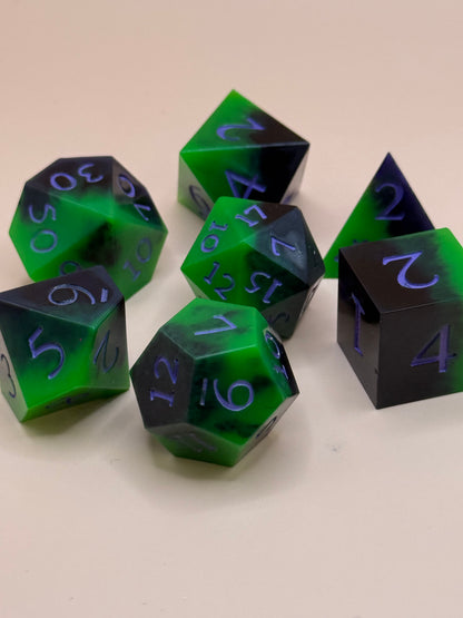 Set of green and black polyhedral dice on a beige background