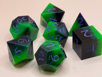 Set of green and black polyhedral dice with purple numbers on a beige background