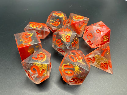 Set of red and clear dice with gold Halloween details and red numbers on a dark surface.