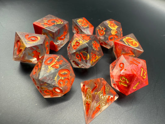 Set of red and clear dice with gold Halloween details and red numbers on a dark surface.