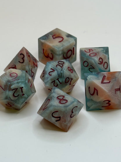 polyhedral sharp-edge, a set of seven in  red, green and bone white held in hands. Numbers are inked in red.