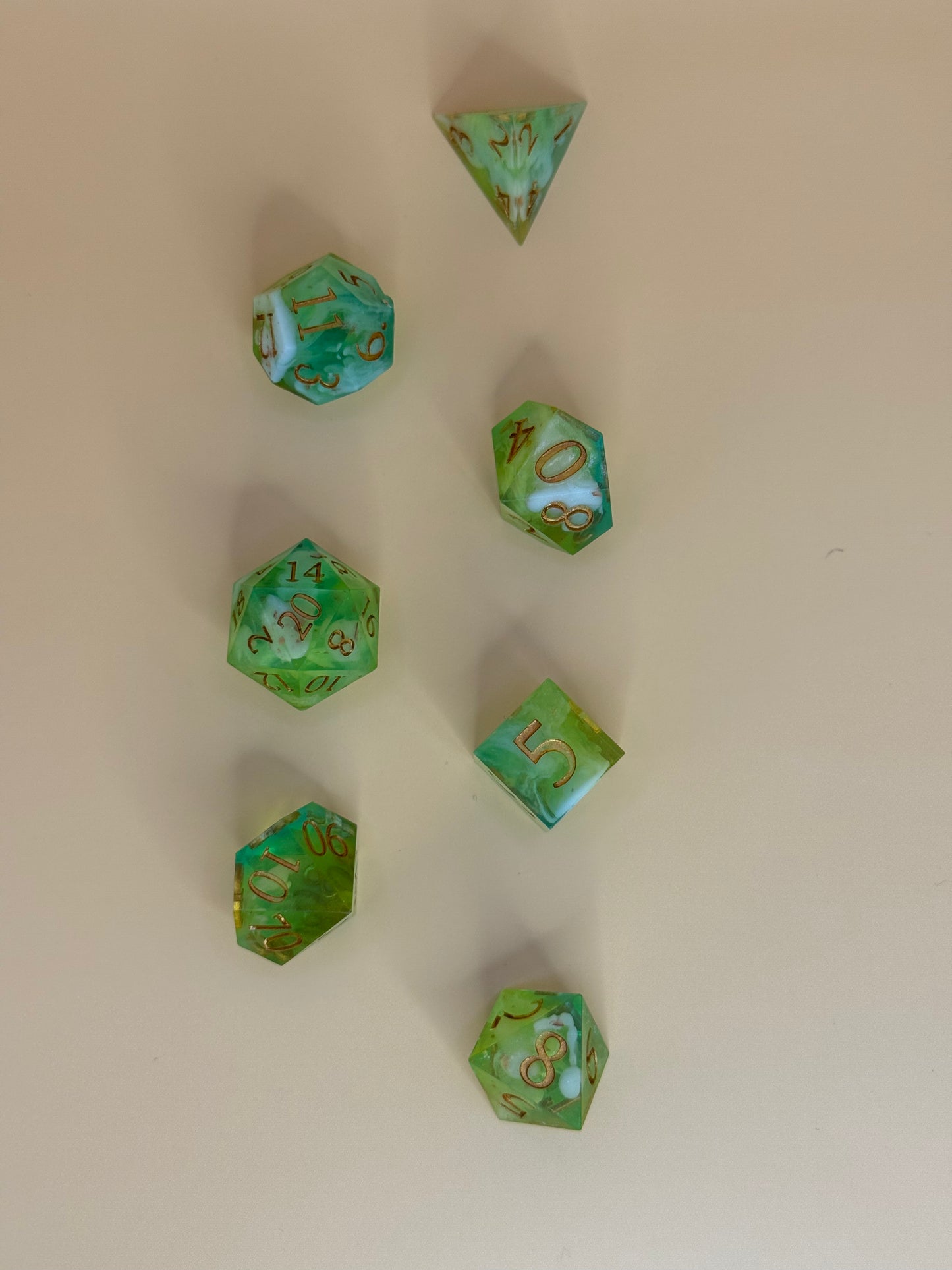 Green polyhedral dice with gold numbers on a beige background