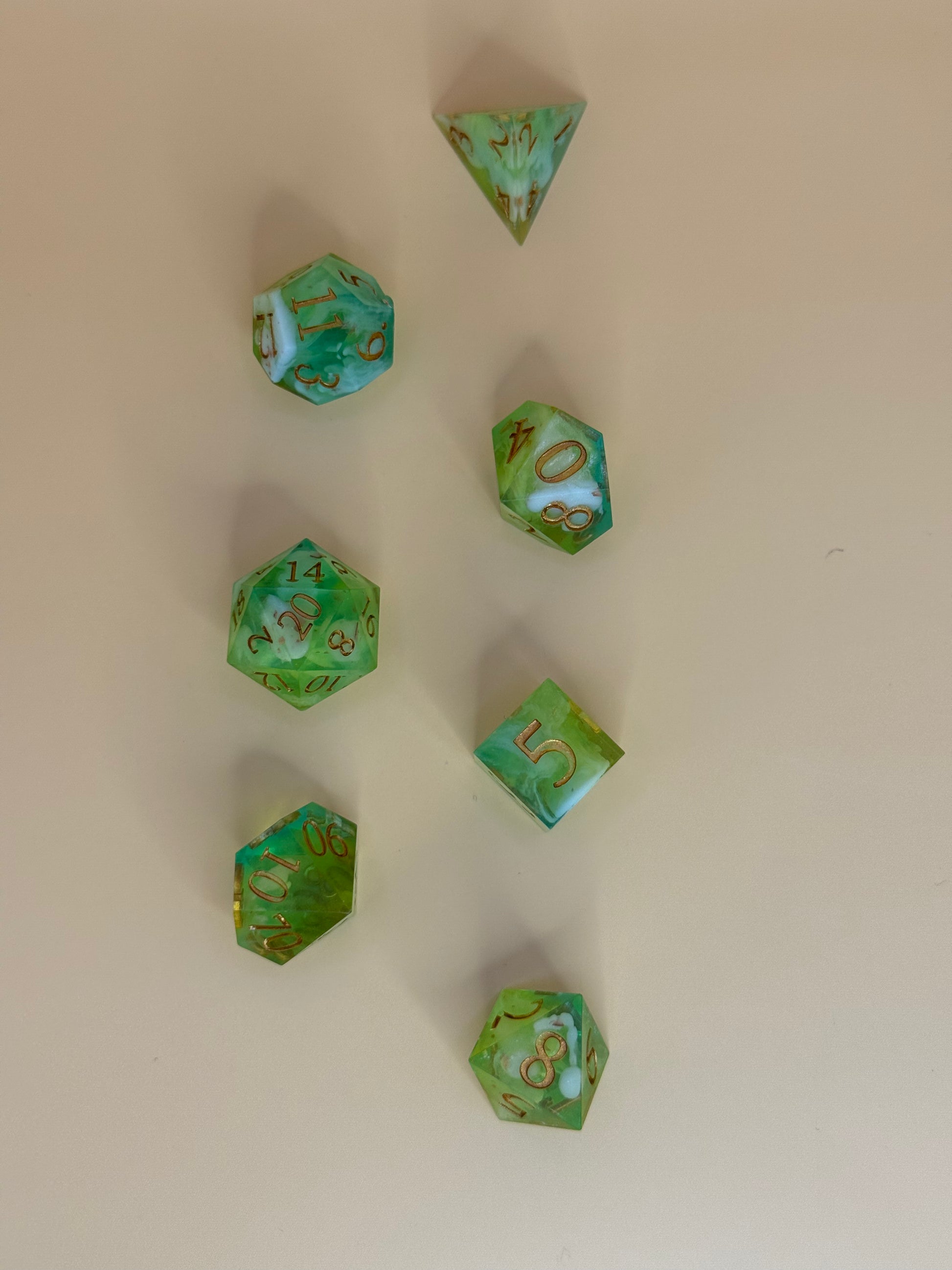Green polyhedral dice with gold numbers on a beige background