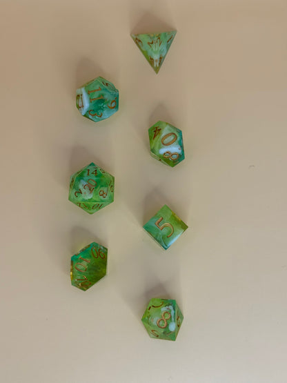 Green polyhedral dice with gold numbers on a beige background