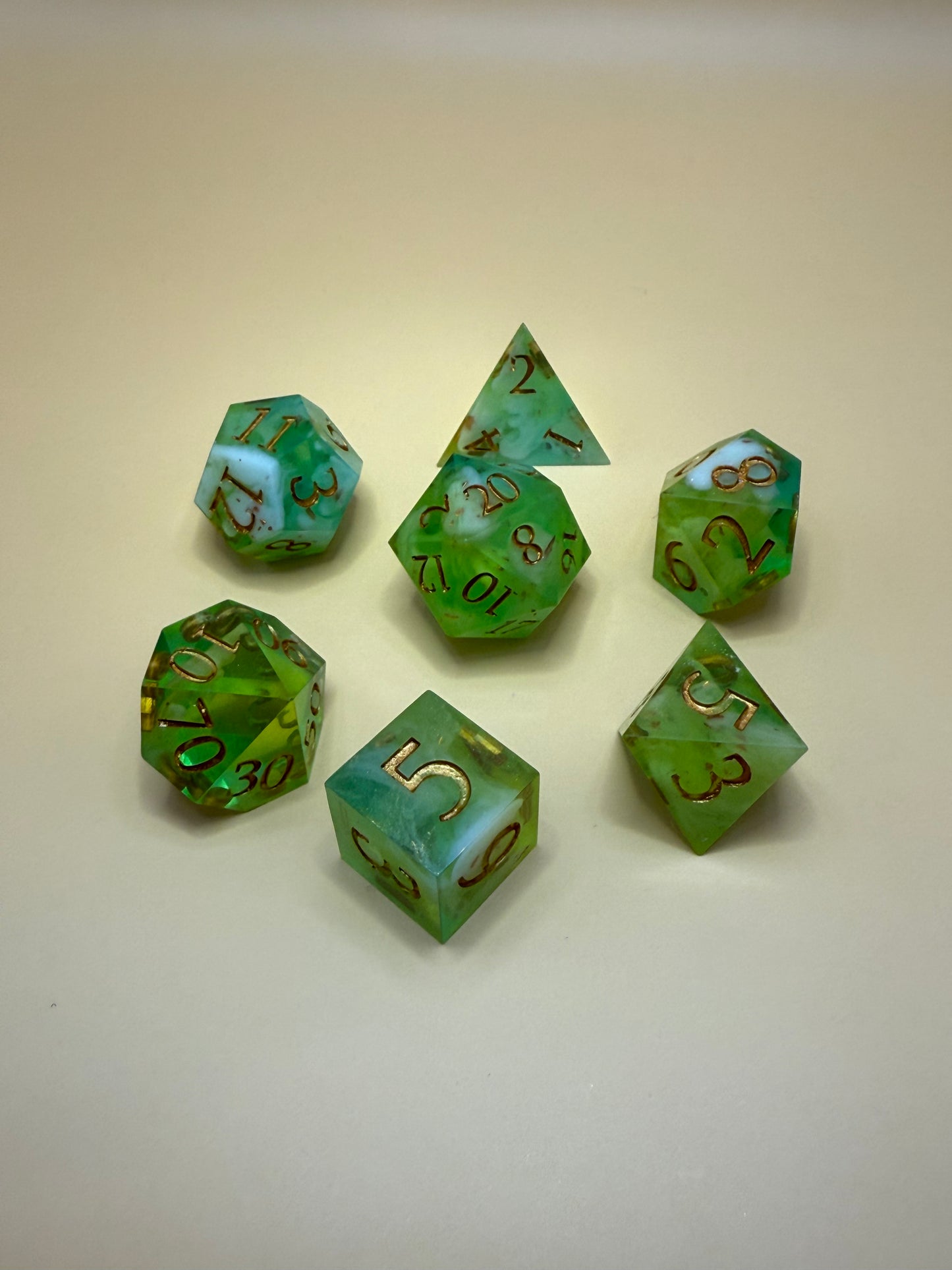 Set of green polyhedral dice with brown numbers on a beige background
