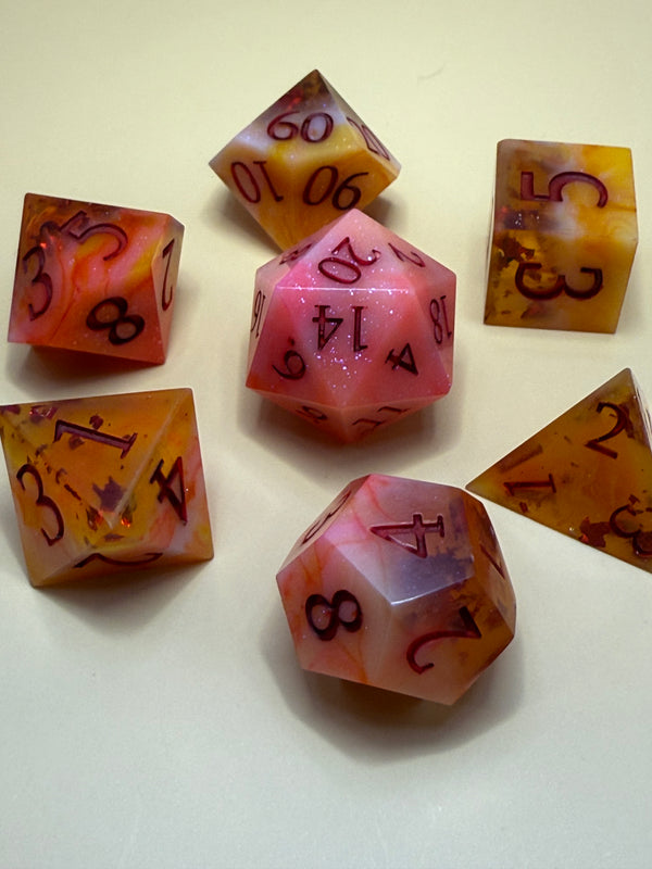 Handmade red and yellow resin polyhedral dice set with glitter on cream background