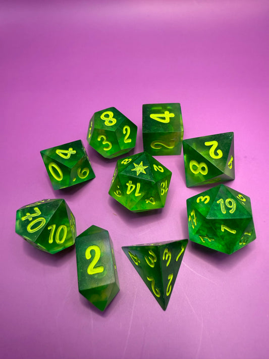 Green polyhedral dice with yellow numbers on a pink background