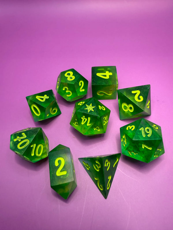 Set of green resin polyhedral dice with yellow numbers on a purple background