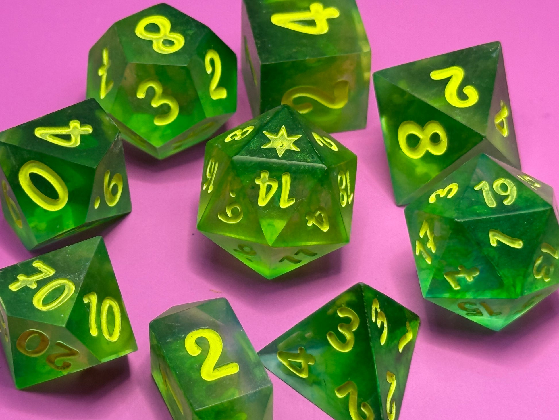Green polyhedral dice with yellow numbers on a pink background