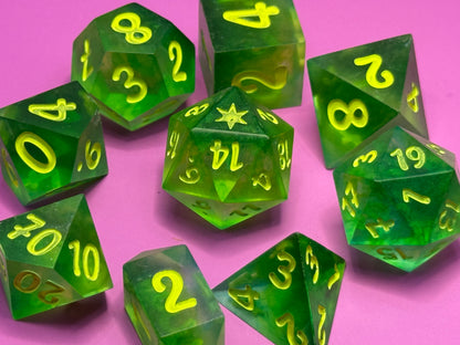 Green polyhedral dice with yellow numbers on a pink background