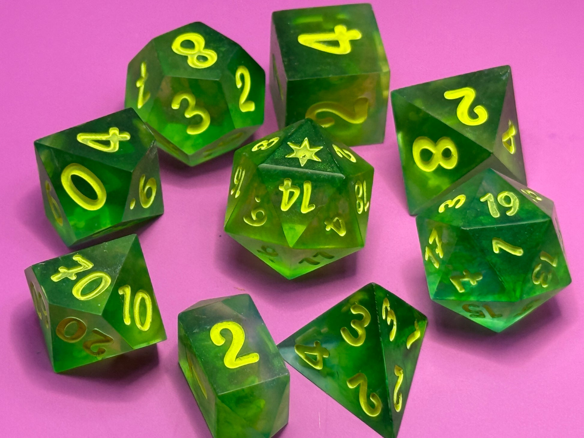 Green polyhedral dice with yellow numbers on a pink background